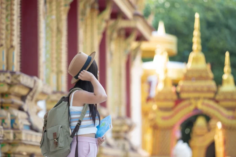 A girl in a temple with backpack and hat in thailand